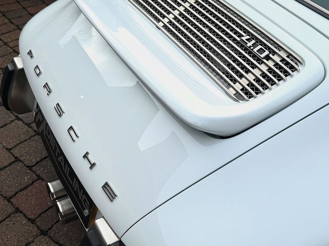 Specialist machine polishing results on a white Porsche 911 Singer 4.0. Close-up of reflective paint clarity and rear decklid mesh following paint correction at FX Detailing studio in Charlwood, Surrey.