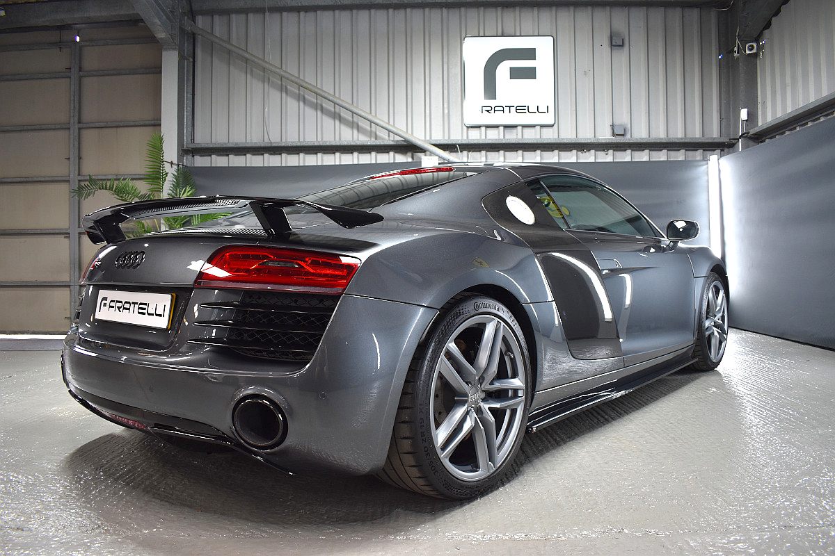 Rear three-quarter of a black Audi R8 with a rear wing and side skirt