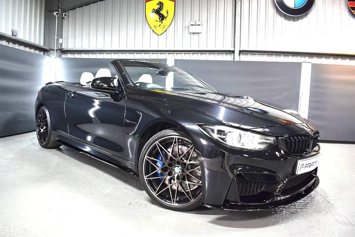 Black BMW M4 convertible with a front splitter, side skirt and black wheels