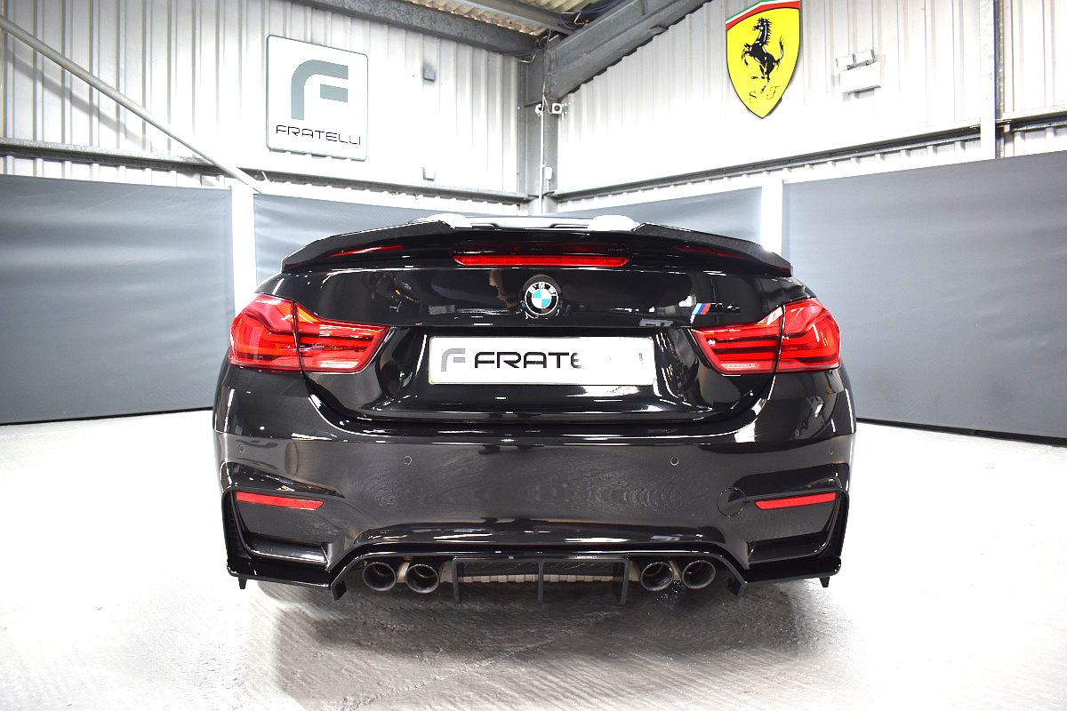 Rear of a black BMW M4 convertible with a diffuser, quad exhausts and boot spoiler