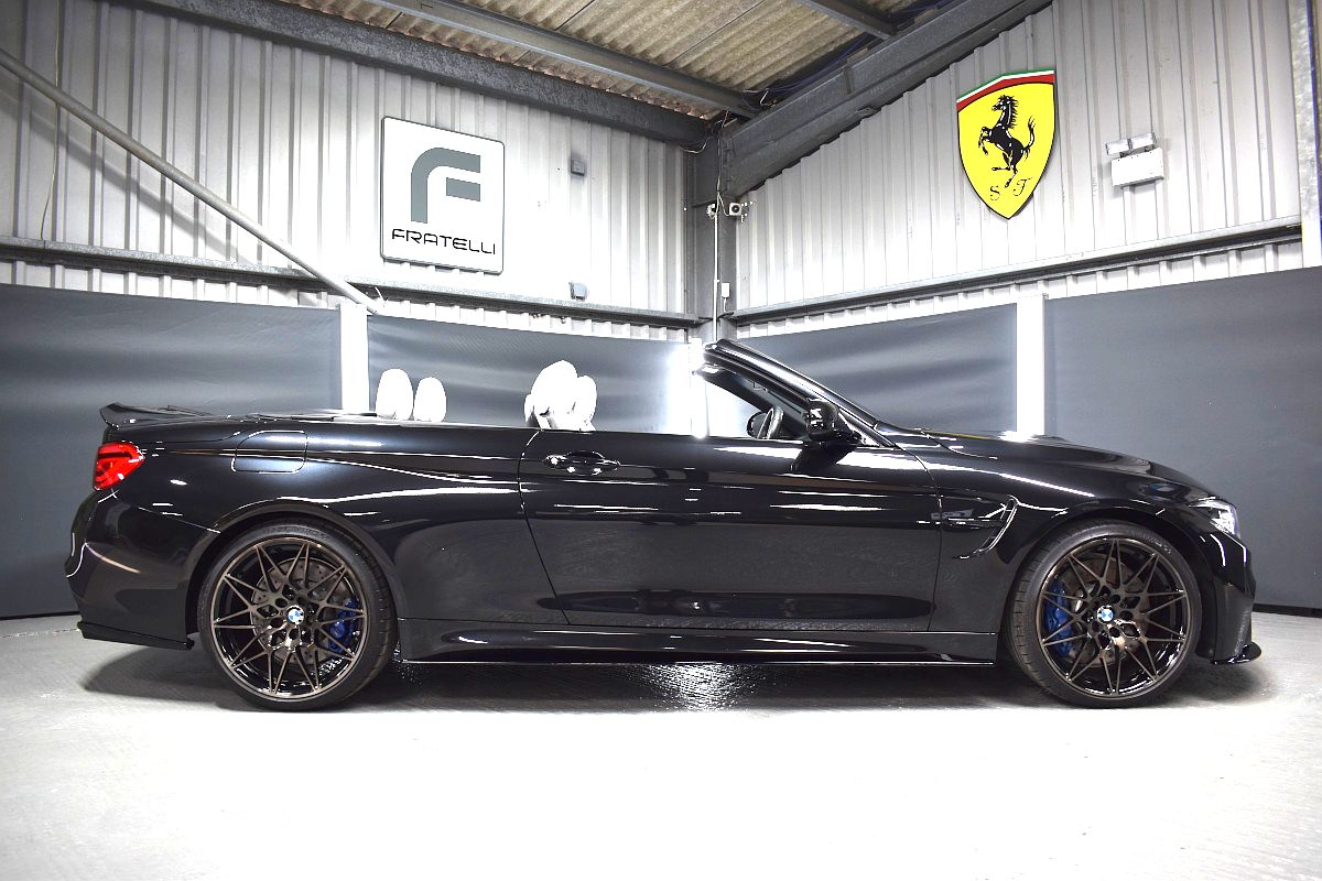 Side of a black BMW M4 convertible with side skirts and a boot spoiler