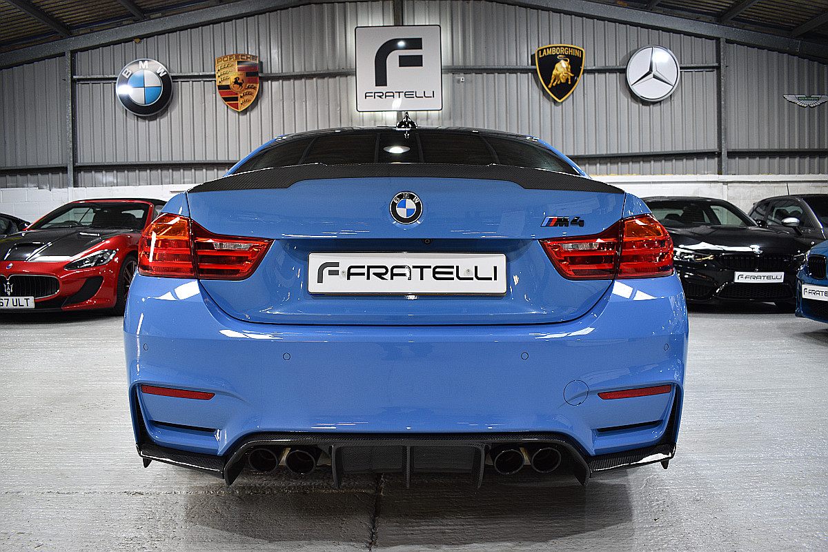 Rear of a light blue BMW M4 with a carbon spoiler and diffuser