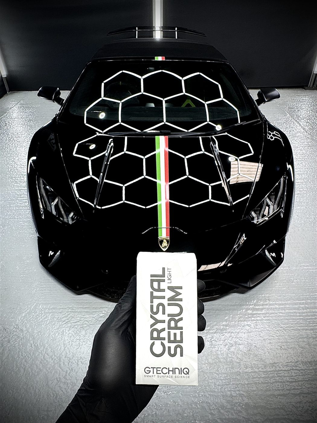 Gtechniq Crystal Serum Light held in front of a black Lamborghini